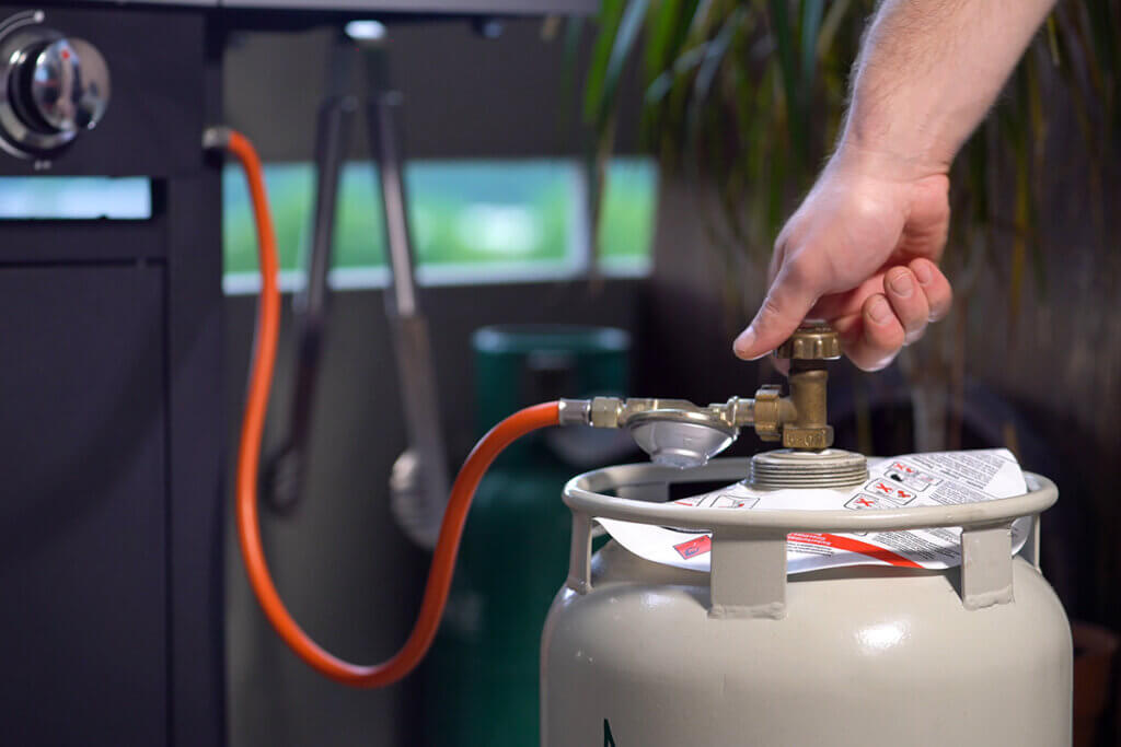 man turns gas for grill on