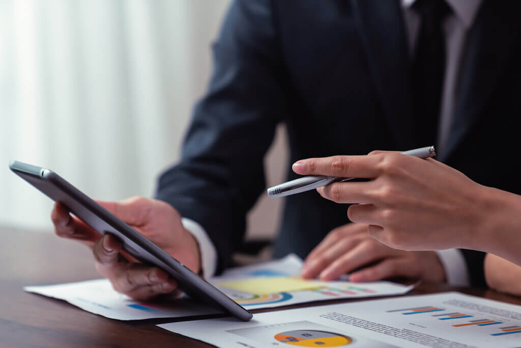 Two people work with one tablet in a business setting.