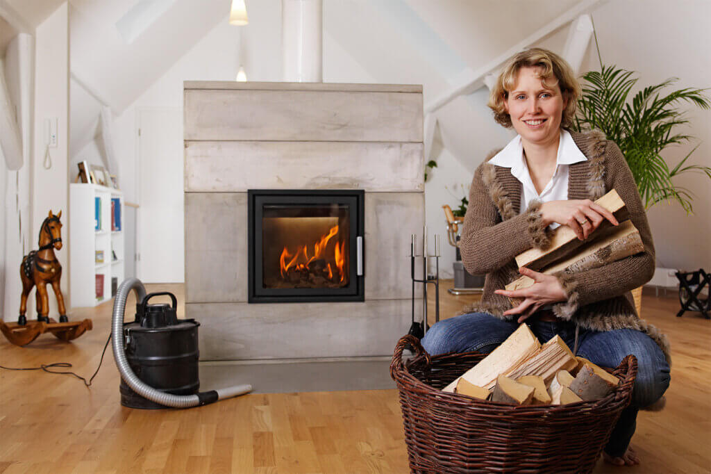Woman with wood on arm in front of fireplace and ash vacuum cleaner