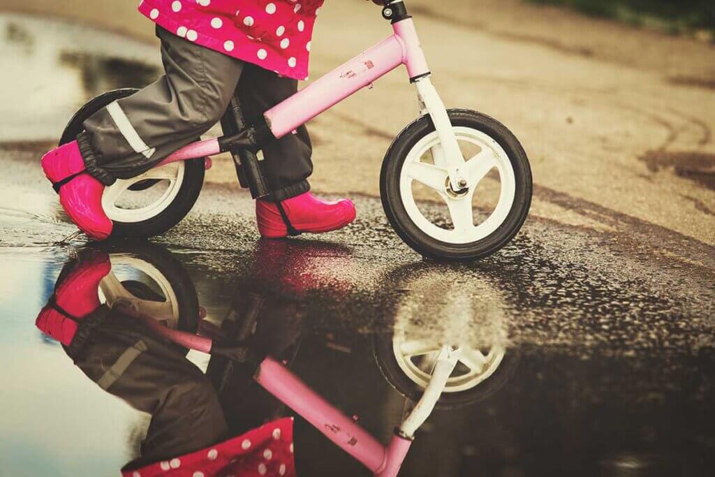 small girl rides with balance bike through paws