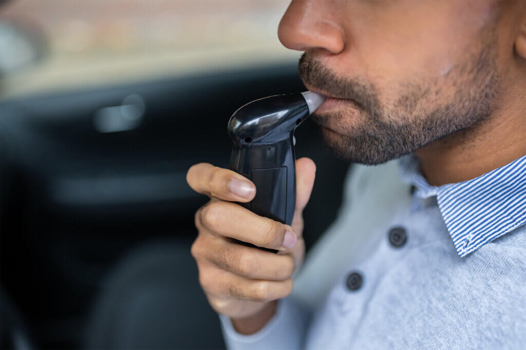 man uses breathalyser in car