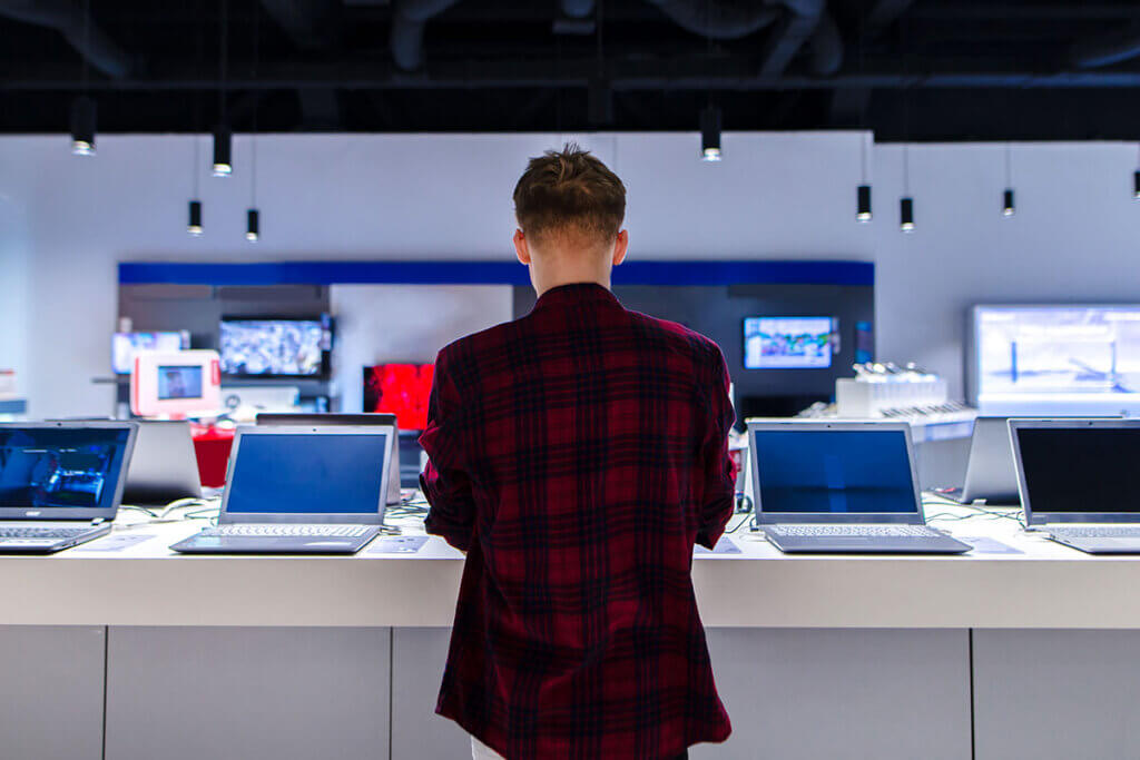 young man stands in front of chromebooks in the shop