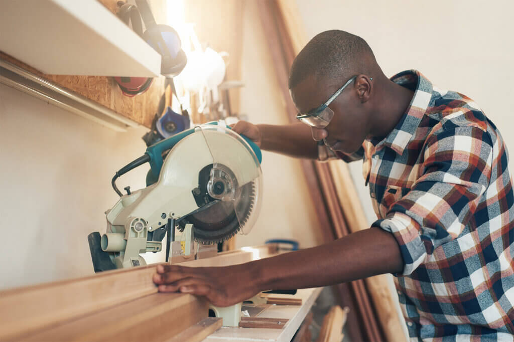 Man cutting wooden planks with crosscut saw