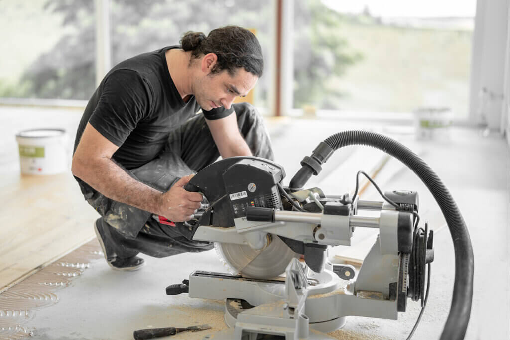 Craftsman cuts wooden plank on building site with crosscut saw