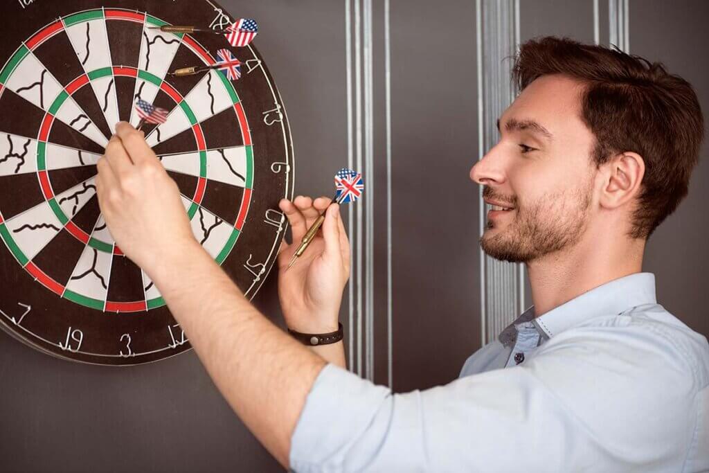 man pulls darts from board