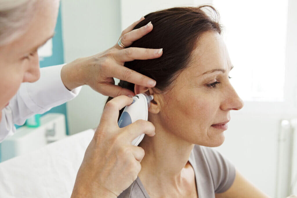 Doctor measuring fever in woman's ear