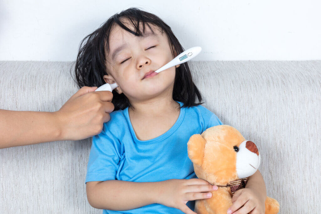 Child with fever thermometer in ear and mouth
