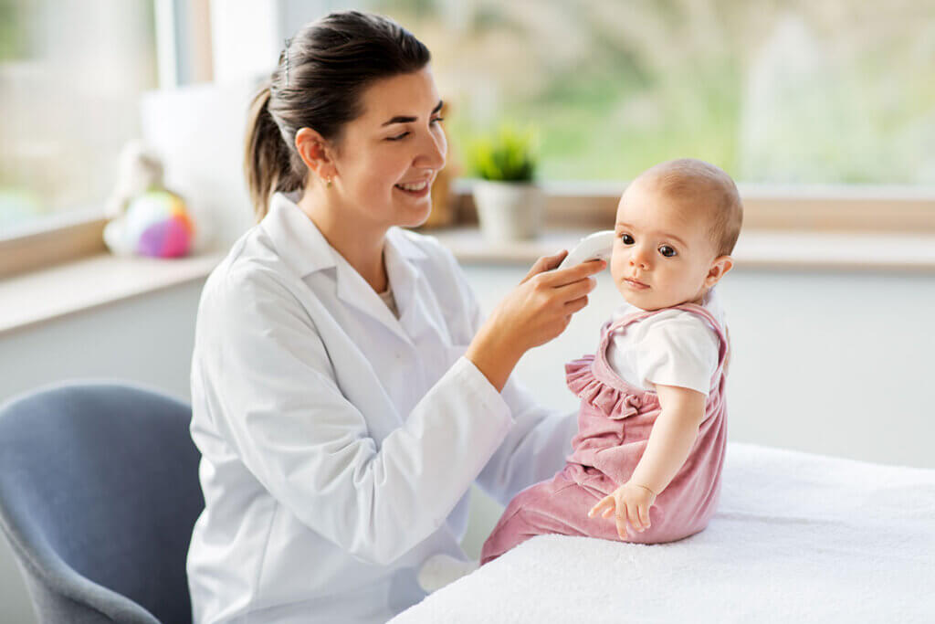 Paediatrician taking temperature of toddler