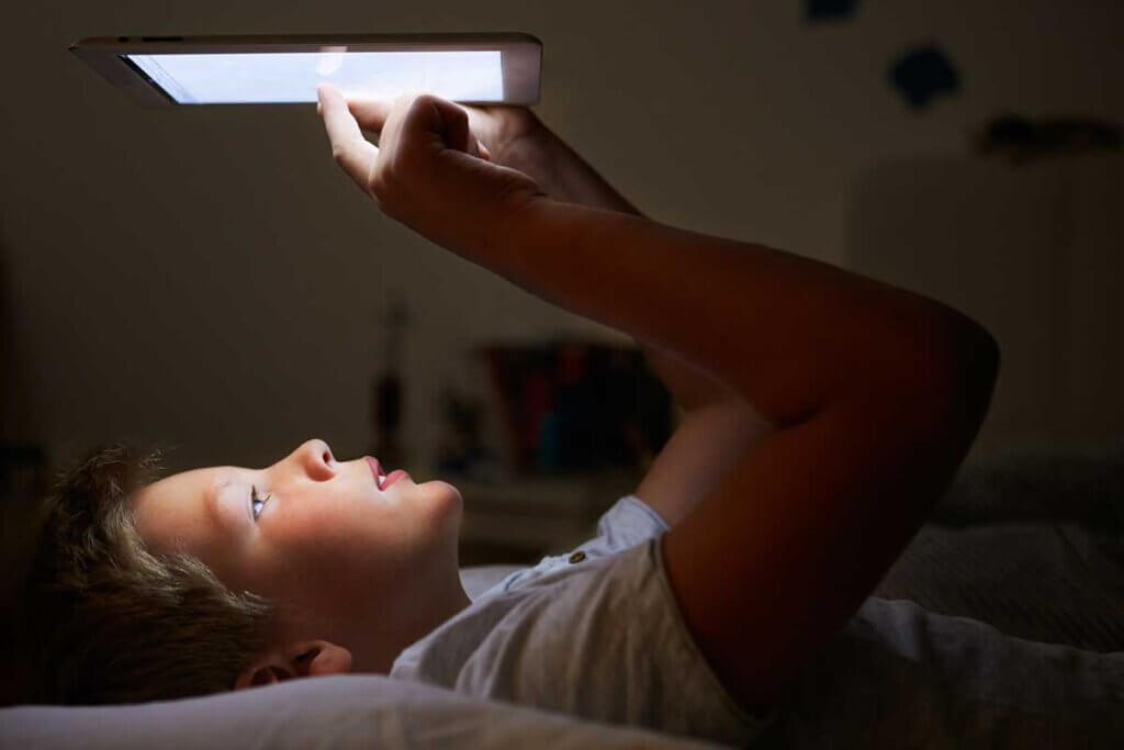 ebook_reader_boy_lying_in_bed_and_reading_on_his_ebook