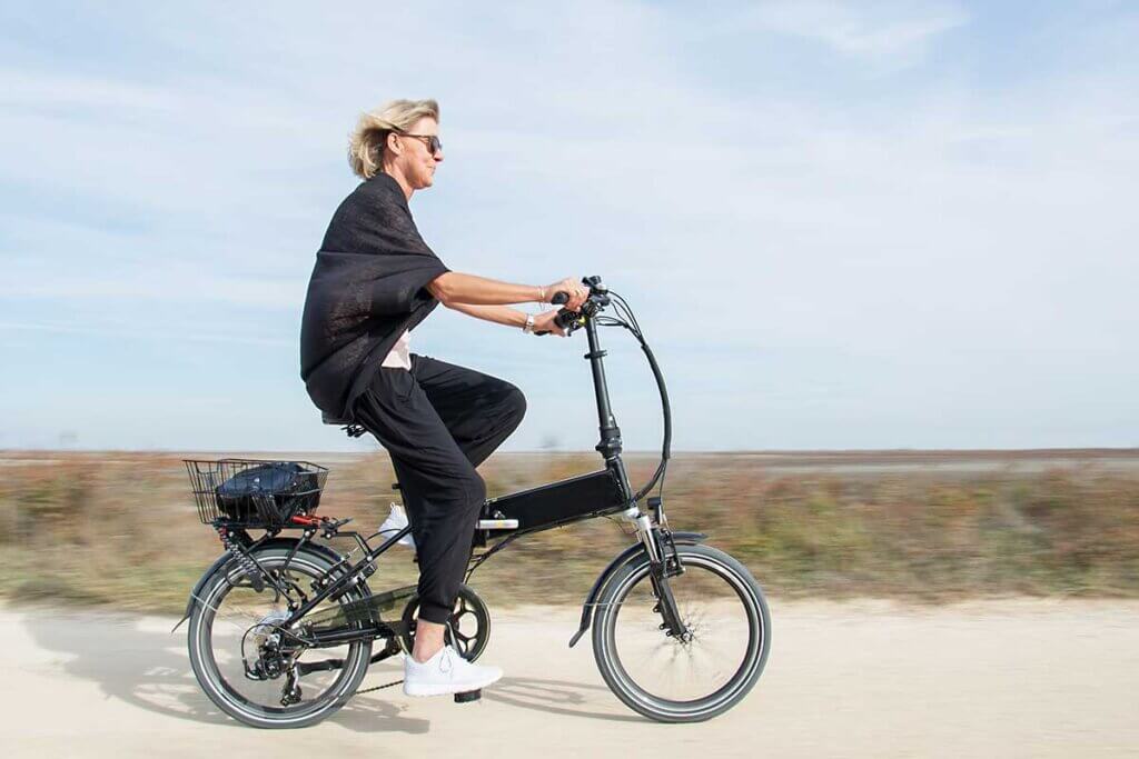 woman riding folding e-bike on beach