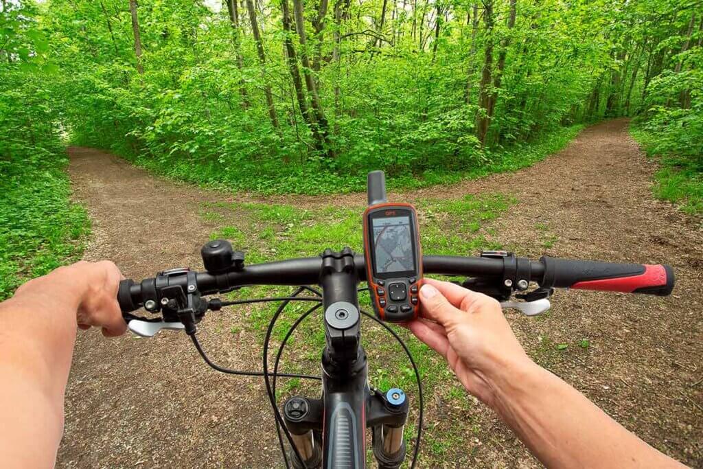 cyclist looks at his navi before crossing a path in the forest