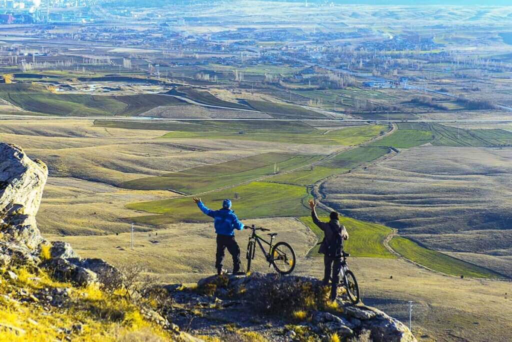 cyclists stand on a mountain and look down on the landscape