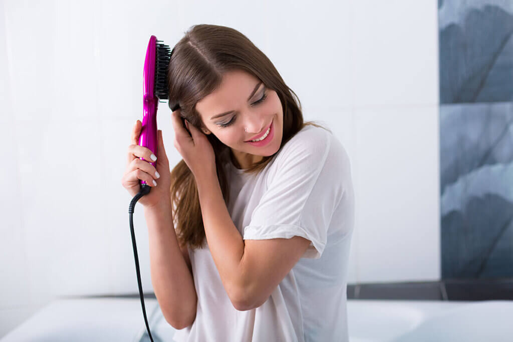 Person straightens their hair with a hair straightener brush