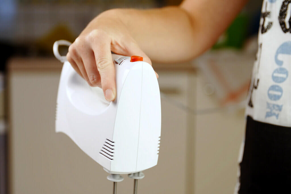 person_holding_hand_mixer_in_kitchen