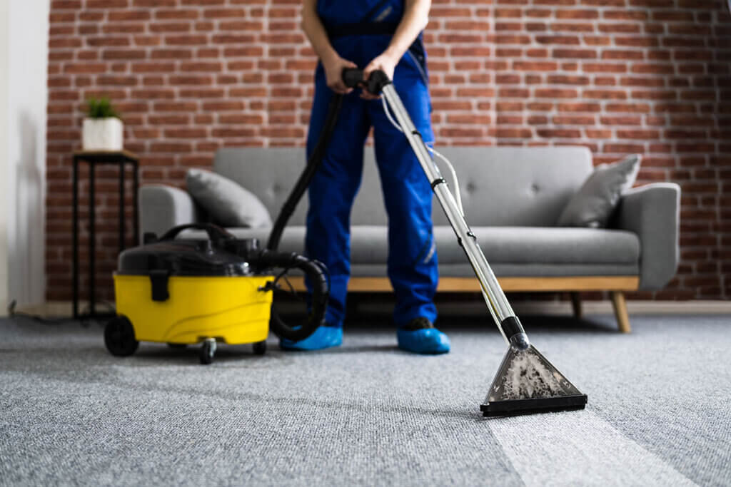 Man cleans carpet with industrial vacuum cleaner