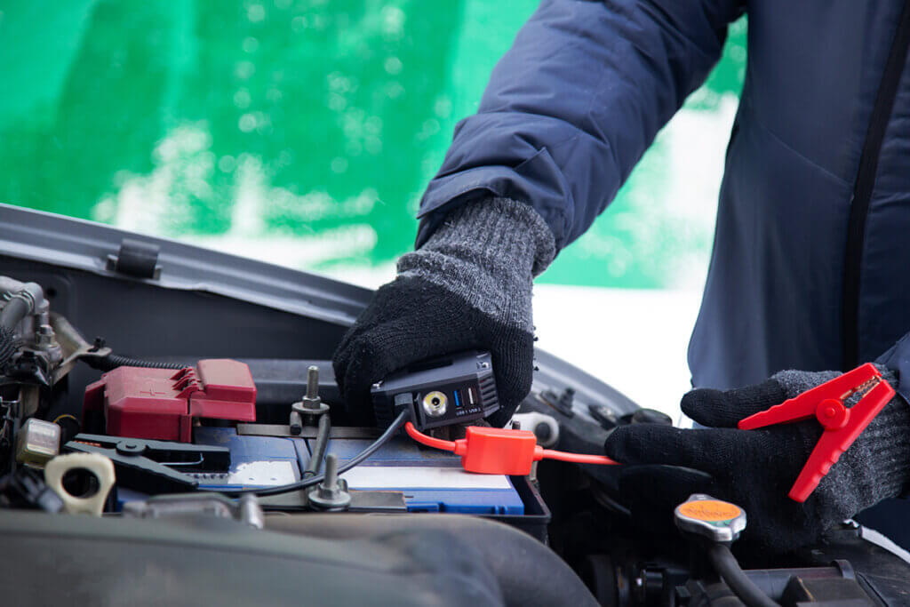 Man connects jump starter to car battery