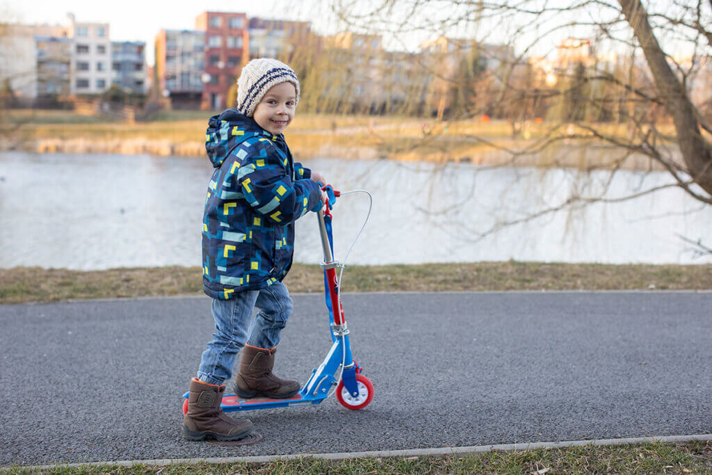 child rides scooter in park