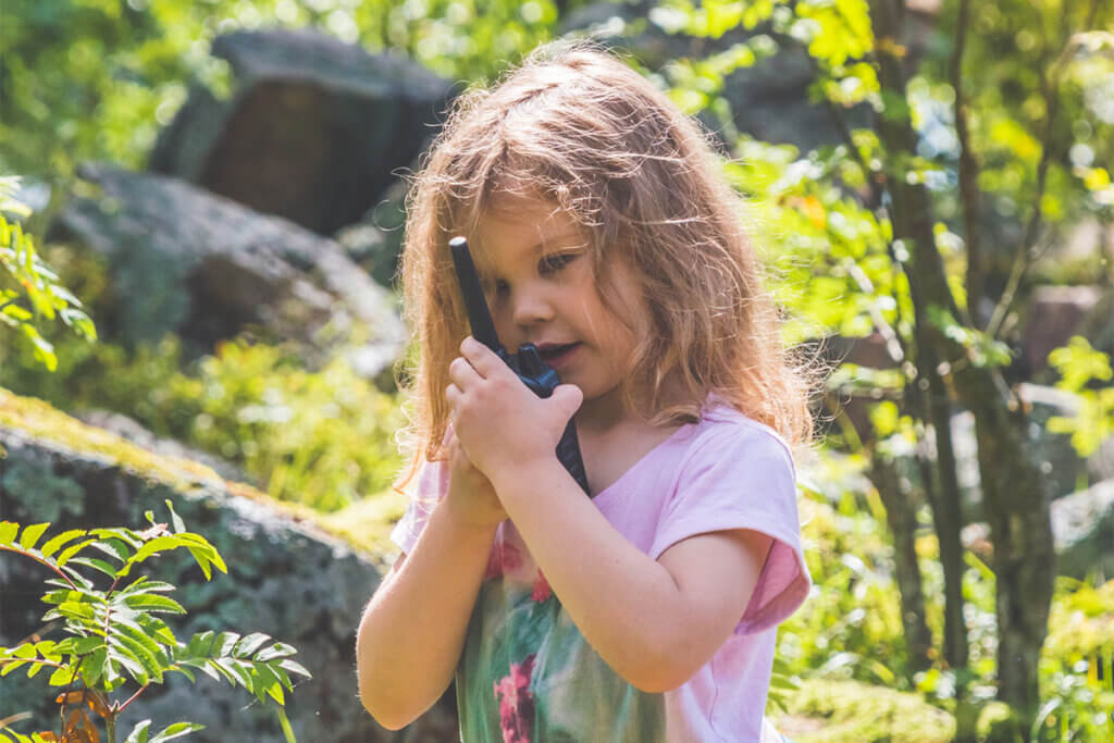 Child talking into a walkie-talkie in the forest