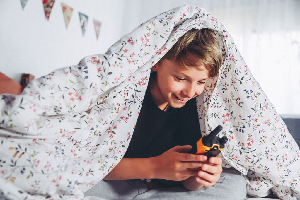 Child playing with a walkie-talkie in bed