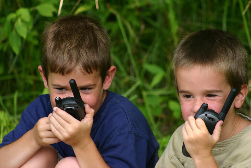 Two boys playing with walkie-talkies outdoors