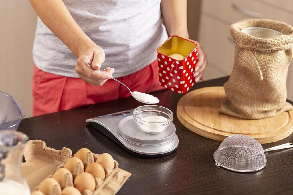 Woman measuring sugar in kitchen