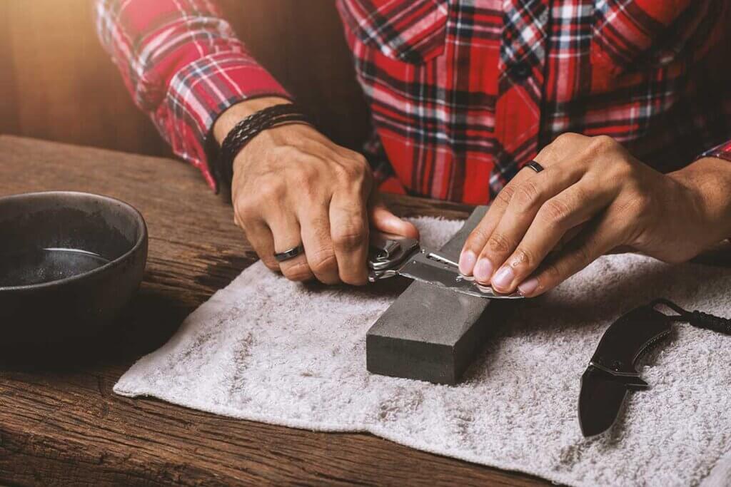 man sharpening blades on whetstone