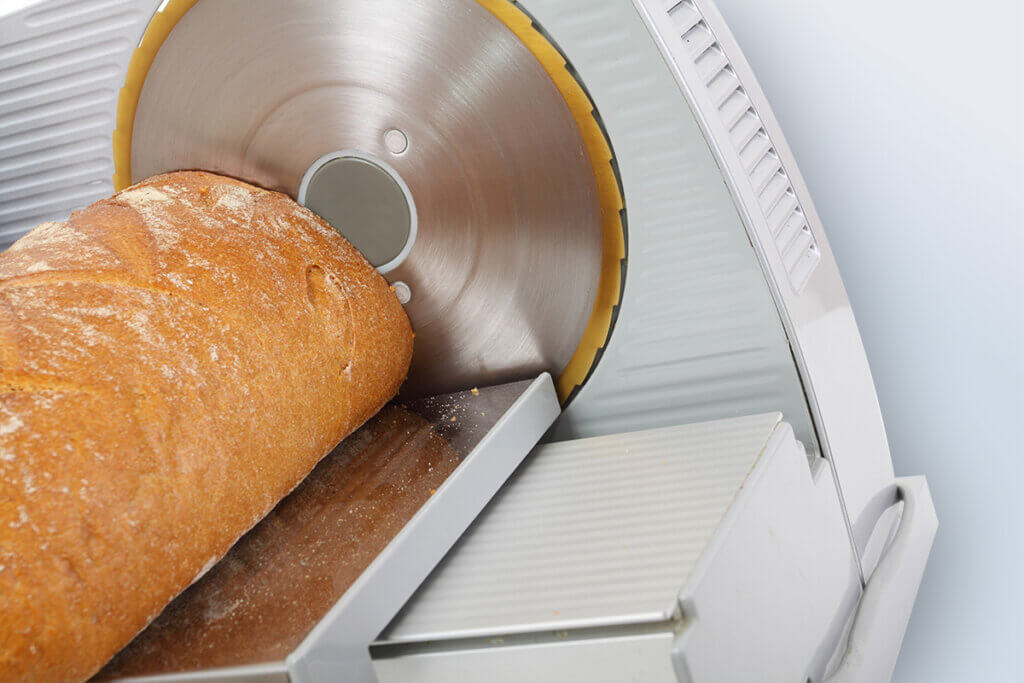 Fresh bread being cut with universal slicer