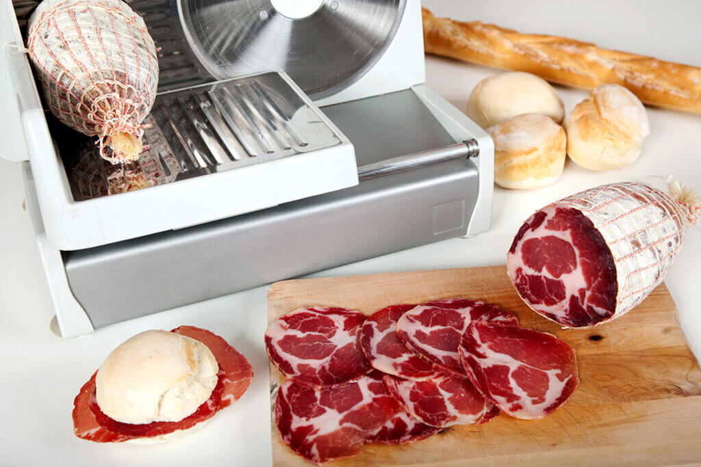 Sliced sausage next to slicer on table