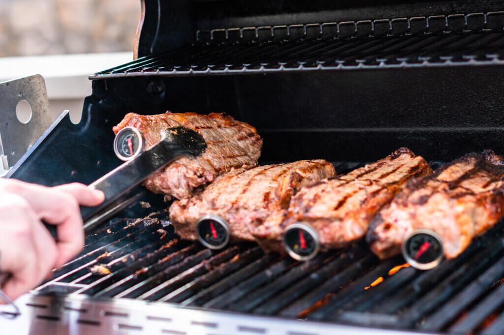 Four steaks with barbecue thermometer