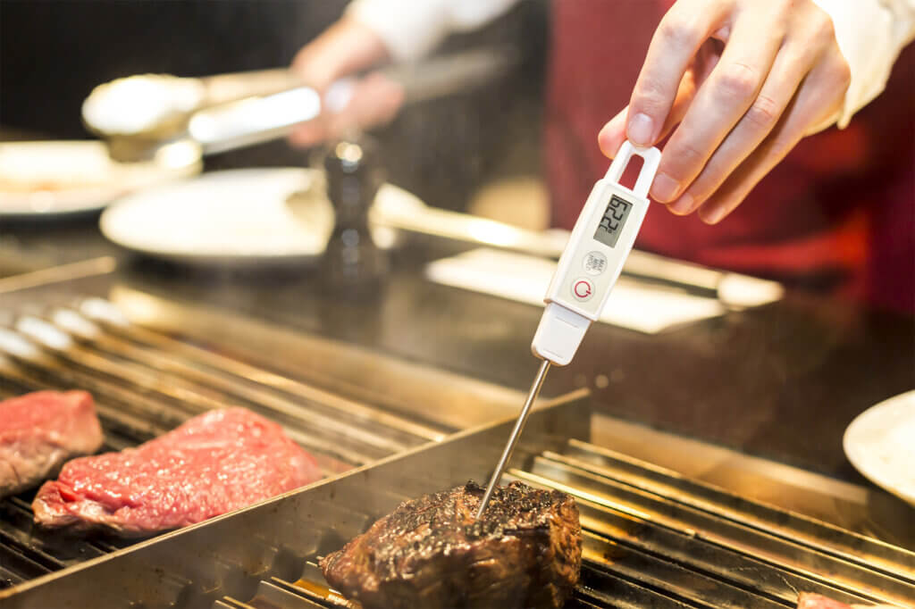 Measuring the temperature of steak on the grill