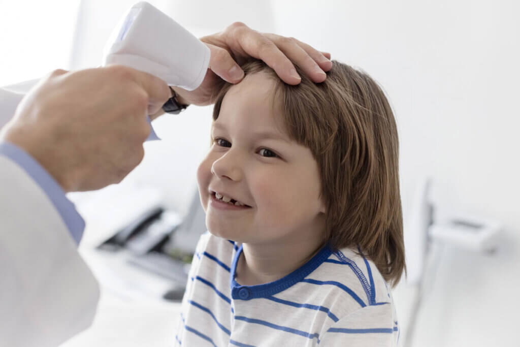 temperature of a boy is measured with forehead thermometer