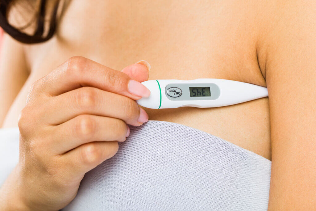 woman measures temperature under the armpits