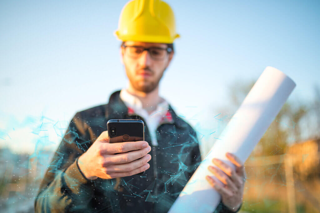 construction worker in hard hat holds outdoor smartphone in hand
