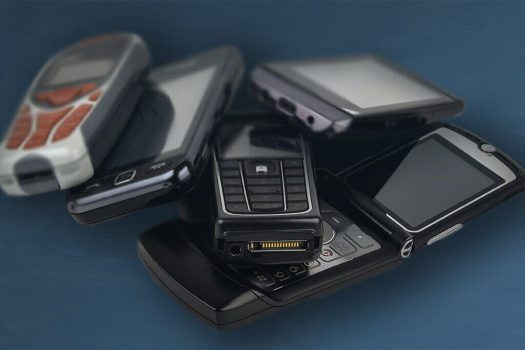 several keypad phones on a table, including a motorola razr v3.