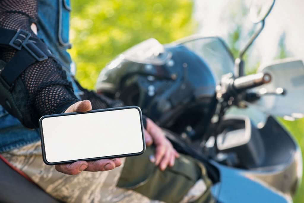 person auf motorrad zeigt smartphone