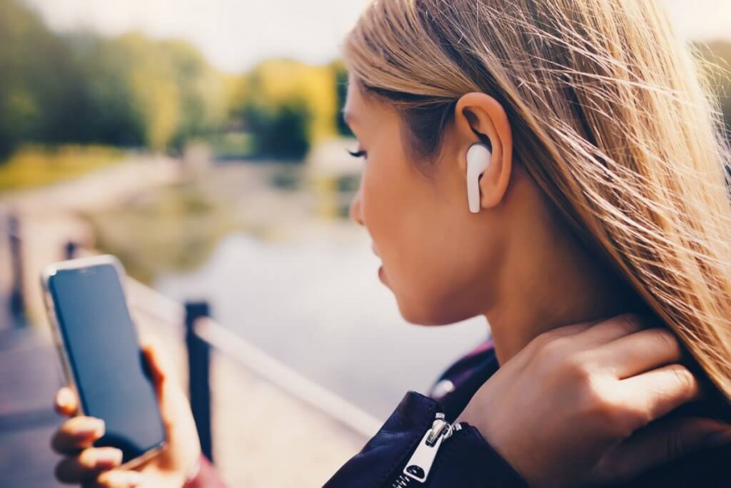 frau in motorradkleidung traegt ear pods