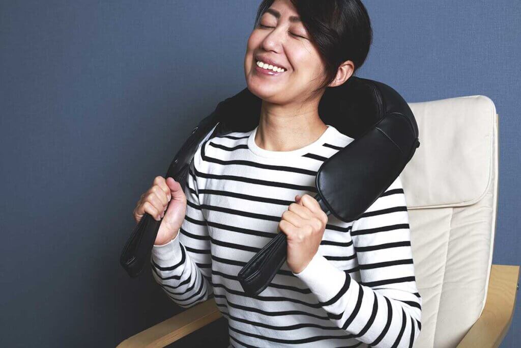 Woman uses neck massager and smiles