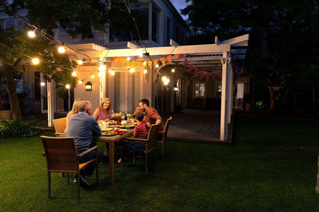 family eats together in the garden with light chain