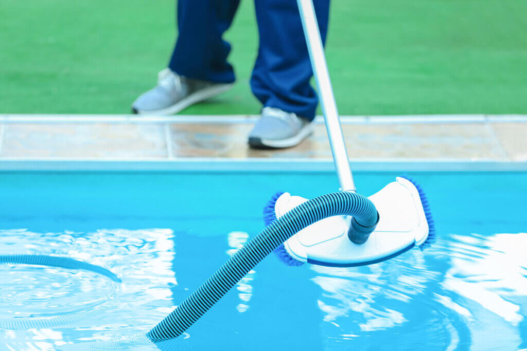 person works with pool vacuum