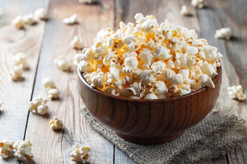 Fresh popcorn in wooden bowl on wooden table