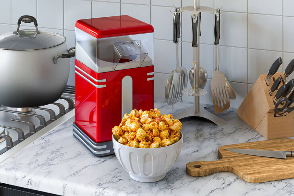 Popcorn machine and bowl full of popcorn are in kitchen