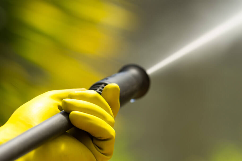 gloved hand holds high pressure washer