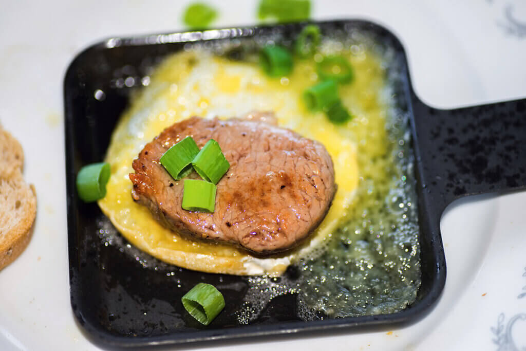 meat and egg in raclette pan