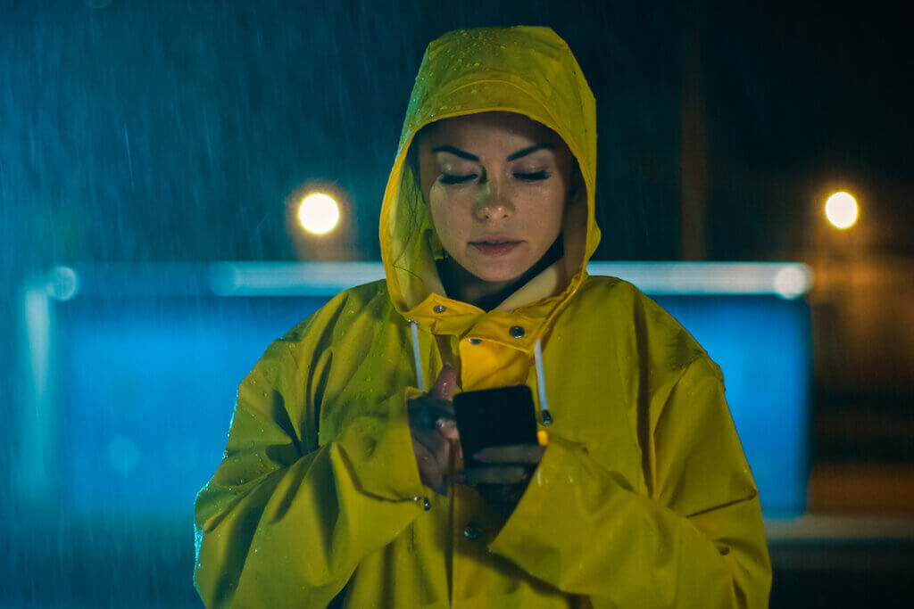 Woman in the rain uses smartphone