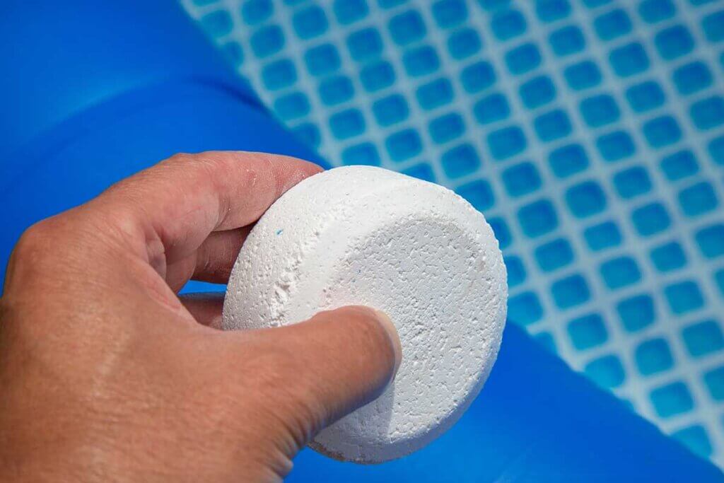man holds chlorine tablet over pool