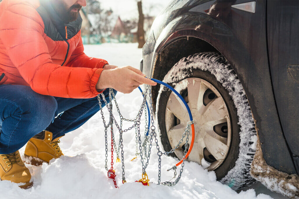 man puts on snow chains