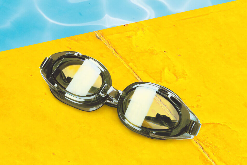 Swimming goggles on yellow pool edge