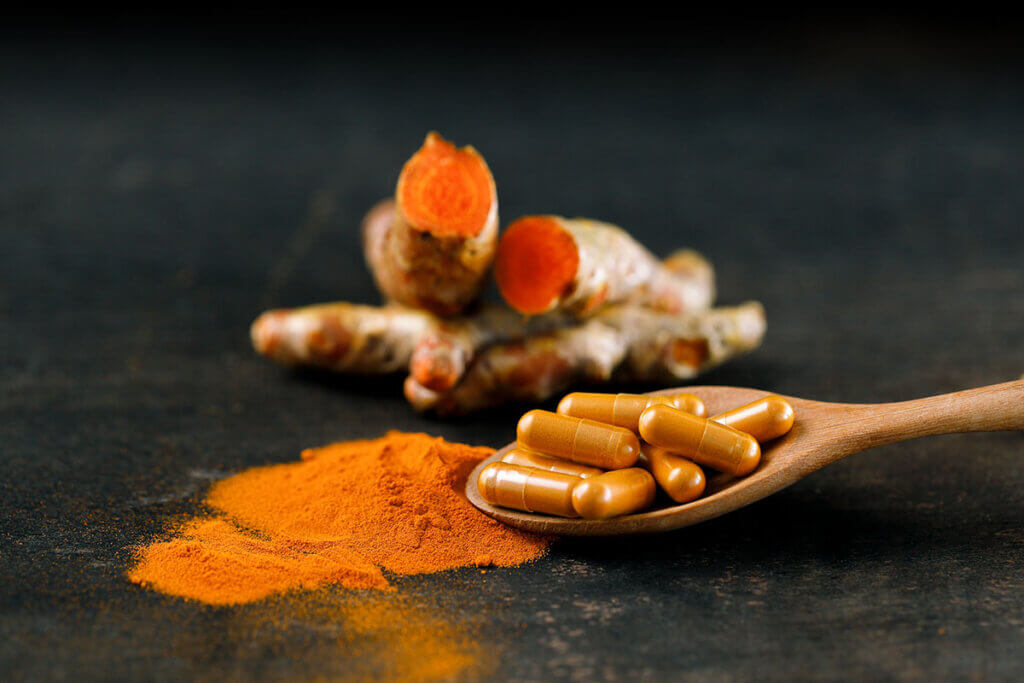 several turmeric capsules on wood lobes