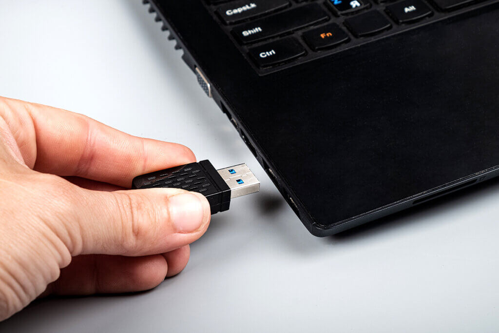 Person inserts WLAN stick into USB slot on laptop